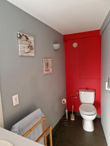 La salle de bains est pourvue d'une porte rouge et de toilettes. dans l'établissement Beau duplex au coeur du village, à Saint-Cyprien