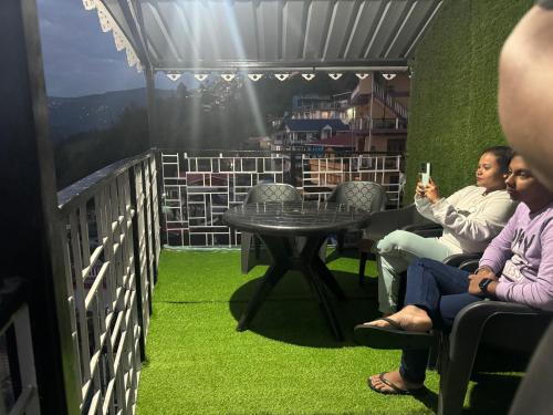 two women sitting on a balcony with a table at AamaHomeStay Suite Room with bath tub in Kurseong