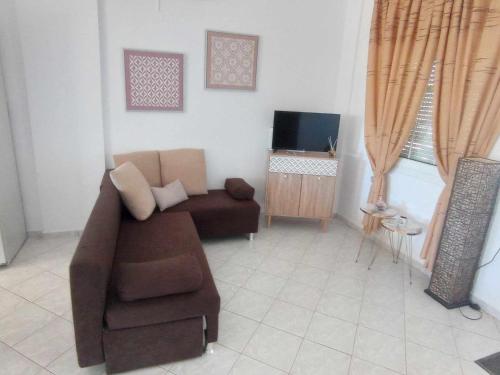 a living room with a couch and a television at GARDEN HOUSE, Kalamaki in Tympáki