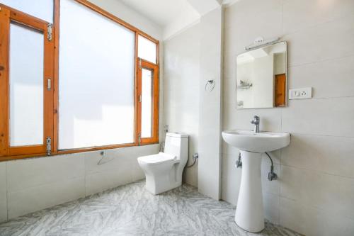 a bathroom with a sink and a toilet and a window at WooibHotels The Kanchanikoot Manali in Manāli