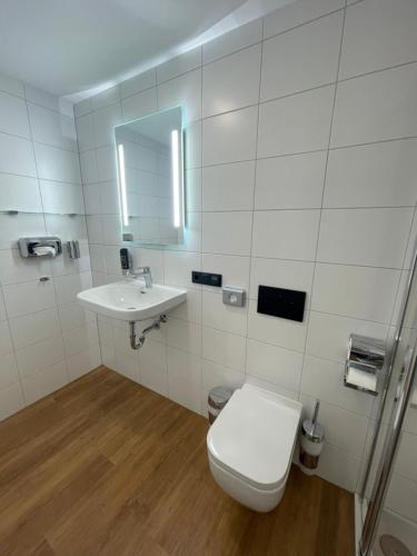 a white bathroom with a toilet and a sink at Hopfenhotel am Adenauerufer in Bamberg