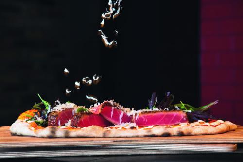 a pizza sitting on top of a wooden cutting board at Mövenpick Hotel Zürich-Regensdorf in Regensdorf