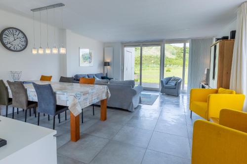 a kitchen and living room with a table and chairs at Hogehilweg 16 vakantiehuis, Direct onder de duinen - eigen parkeerplaatsen in Domburg
