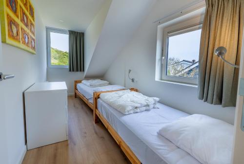 two beds in a room with two windows at Hogehilweg 16 vakantiehuis, Direct onder de duinen - eigen parkeerplaatsen in Domburg