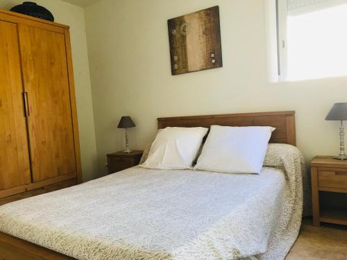 une chambre avec un lit avec des draps blancs et des oreillers dans l'établissement Rez de chaussez de villa 4 personnes mer, à Sorbo-Ocagnano