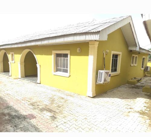 une maison jaune avec une allée en briques dans l'établissement Inviting 2-Bed House in Abeokuta, à Abeokuta