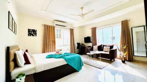 Olive Service Apartments New Town في كولْكاتا: غرفة نوم بسرير واريكة وكرسي