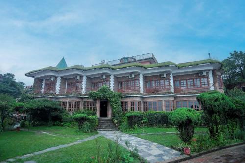 a large building with a grass yard in front of it at Mountain Vista Retreat in Nagarkot