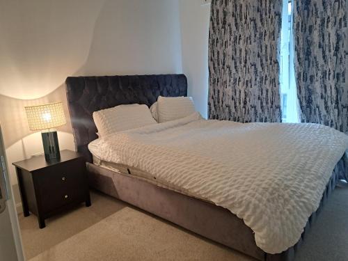 a bedroom with a large bed with a nightstand and a window at Stunning Station Apartment in Kent