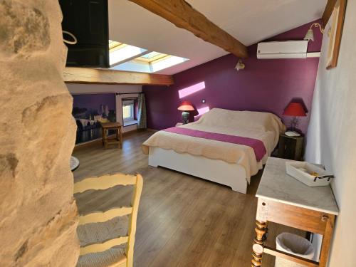 1 dormitorio con paredes de color púrpura, 1 cama y 1 mesa en La vigne appartement, en Sablet
