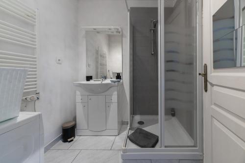 une salle de bain blanche avec une douche et un lavabo dans l'établissement Résidence Nature - Appartements design en centre ville, à Cusset