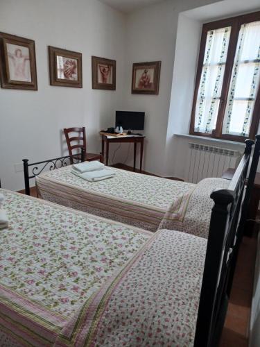 a bedroom with two beds and a desk with a computer at Casa di Adriano in Radicofani