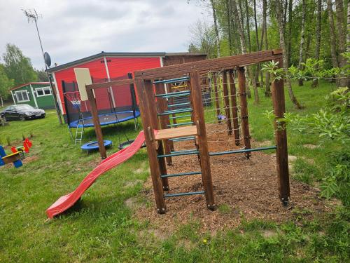 a playground with a slide in a yard at Domek letniskowy - czerwony całoroczny in Stegers