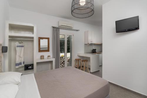 a white bedroom with a bed and a kitchen at Studios Kymata in Pollonia