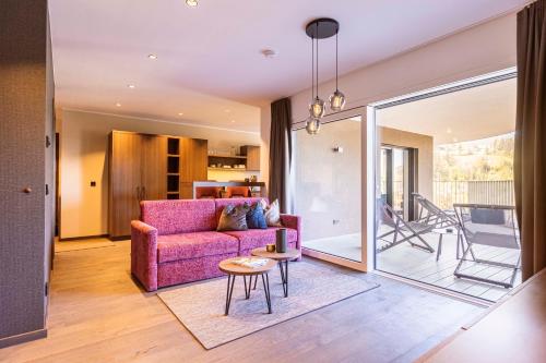 a living room with a pink couch and a table at Brixental Suites Hopfgarten by ALPS RESORTS in Hopfgarten im Brixental