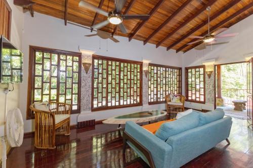 a living room with a blue couch and some windows at Restful Casa Quetzal Luxurious Rainforest Retreat in Quepos