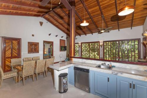 a kitchen with a sink and a counter with chairs at Restful Casa Quetzal Luxurious Rainforest Retreat in Quepos
