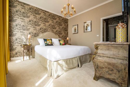 a bedroom with a bed and a chandelier at Hôtel de la Poste à Avallon, Bourgogne in Avallon