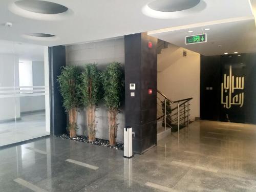 a lobby with a row of palm trees on the wall at Saraya Al Olaya Tower family house in Al Khobar