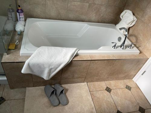 a bath tub with a towel and two slippers in a bathroom at 43 Ave Farm House Langley in Aldergrove