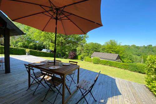 een houten tafel en stoelen met een parasol op een terras bij Charming Normandy House in Fort-Moville