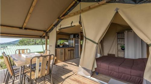 une tente avec une table et un lit. dans l'établissement Camping La Vaugelette - Drôme, à Montclar Sur Gervanne