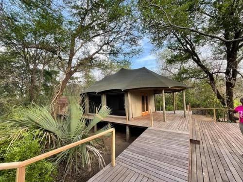 - un kiosque sur une terrasse en bois à côté d'un pont en bois dans l'établissement Muzimu Lodge, 