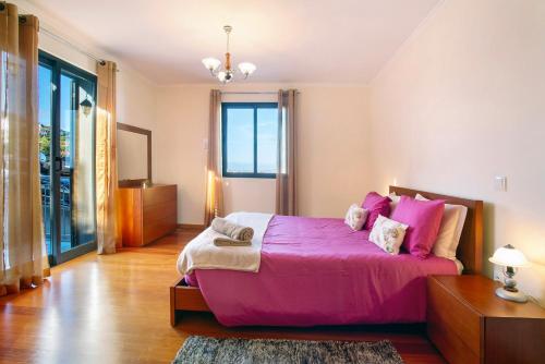un grande letto rosa in una stanza con finestra di Casa da Bemposta a Machico
