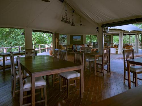 une salle à manger avec des tables et des chaises en bois dans l'établissement Muzimu Lodge, 
