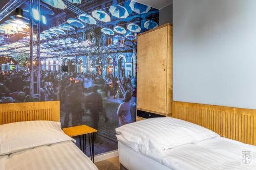a bedroom with two beds and a painting on the wall at Flamingo Centrum in Łódź