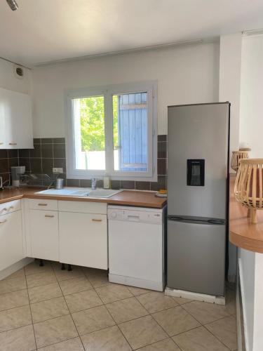 a kitchen with white cabinets and a refrigerator at Maison calme et fonctionnelle business sportifs et familles PAS DE FETE in Corbeil-Essonnes