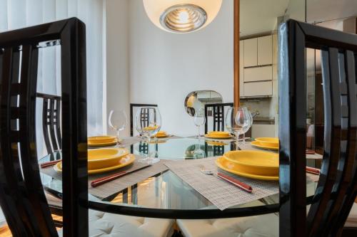 a dining room with a glass table with yellow plates at Villetta con Giardino allo Stadio by Wonderful Italy in Turin