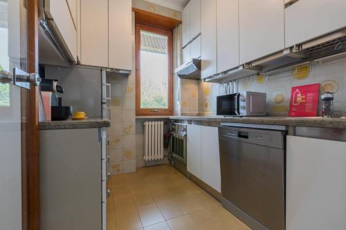 a kitchen with white cabinets and stainless steel appliances at Villetta con Giardino allo Stadio by Wonderful Italy in Turin