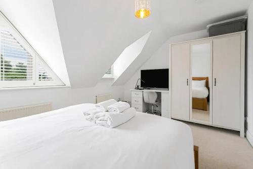 a white bedroom with a white bed and a tv at Richmond Oasis - Pass The Keys in London