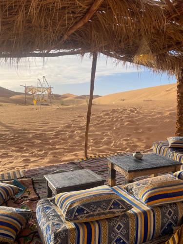 a hut with chairs and a table in the desert at Traditional Luxury Camp in Hassilabied