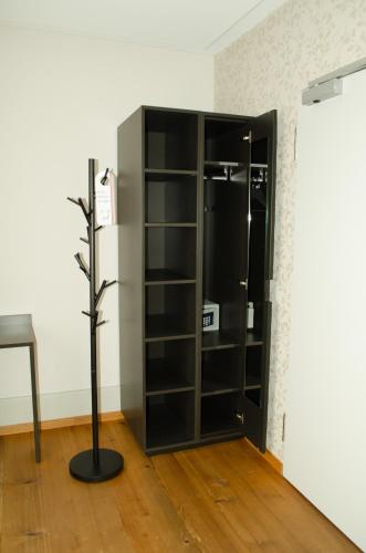 a black book shelf in a room with a tree at Concept Hotel Landhaus - Digital Hotel in Burgdorf