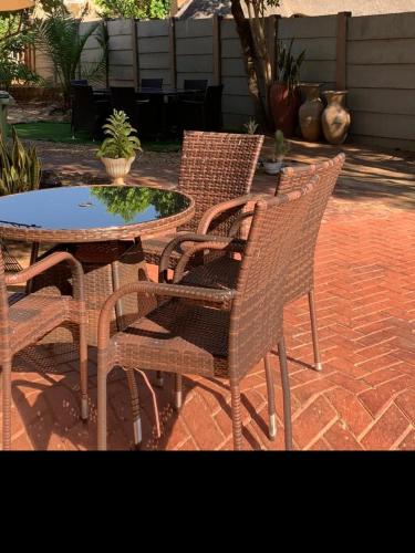 un grupo de sillas de mimbre y una mesa en un patio en Self-Catering Garden Flat in Hochlandpark - 5min from Widhdoek CBD, en Windhoek