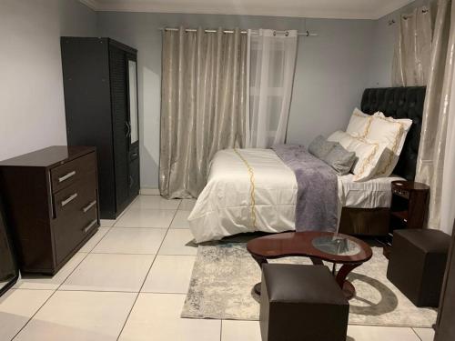1 dormitorio con cama, tocador y mesa en Self-Catering Garden Flat in Hochlandpark - 5min from Widhdoek CBD, en Windhoek