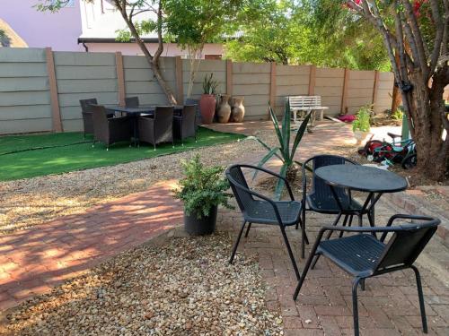 un patio con 2 sillas, una mesa y una mesa con sillas en Self-Catering Garden Flat in Hochlandpark - 5min from Widhdoek CBD, en Windhoek