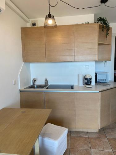 une cuisine avec des armoires en bois, un évier et une table dans l'établissement Appartement vue mer, à Villefranche-sur-Mer