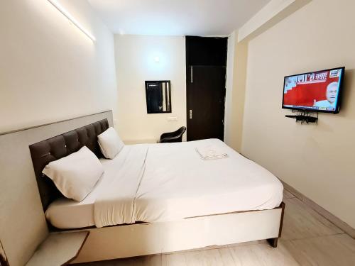 a bedroom with a bed and a tv on a wall at Roomshala 160 Hotel Red - Vasant Kunj in New Delhi
