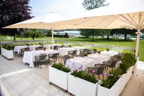 um restaurante com mesas brancas e guarda-sóis brancos em Phyllis Court Members Club em Henley on Thames