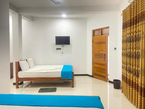 a bedroom with a bed and a tv on the wall at La Maison Yala in Tissamaharama