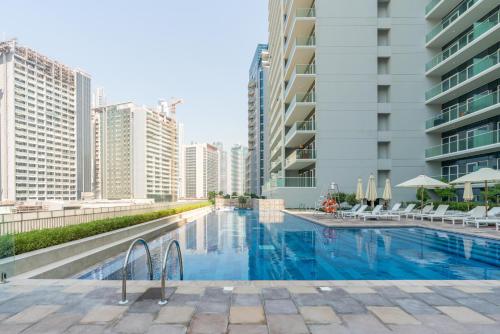 a swimming pool in a city with tall buildings at Delightful 2BR apartment at Reva Residences in Dubai