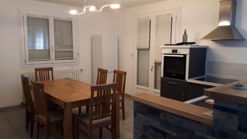 une cuisine avec une table et des chaises en bois ainsi qu'une cuisine avec une cuisinière dans l'établissement Appartement dans maison, à Saint-Étienne-le-Laus