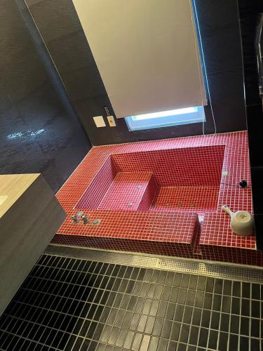a bathroom with red tiles and a sink with a toilet at Ya Nold Hot Spring Hotel in Jiaoxi