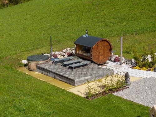 a small round house with a group of benches at Casera Cornolera in Chies dʼAlpago