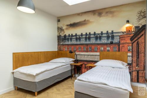 two beds in a room with a painting on the wall at Flamingo Centrum in Łódź