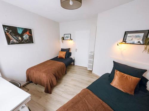 une petite chambre avec deux lits et une table dans l'établissement Cozy 2 bedroom Artbnb Toulouse train station Garage Wi-Fi, à Toulouse