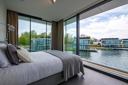 a bedroom with a large window with a view of the water at Dormio Harbour Village in Arnemuiden